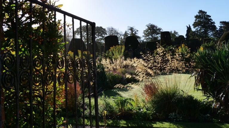 A view through a gate to the gardens in autumn at Packwood, Warwickshire